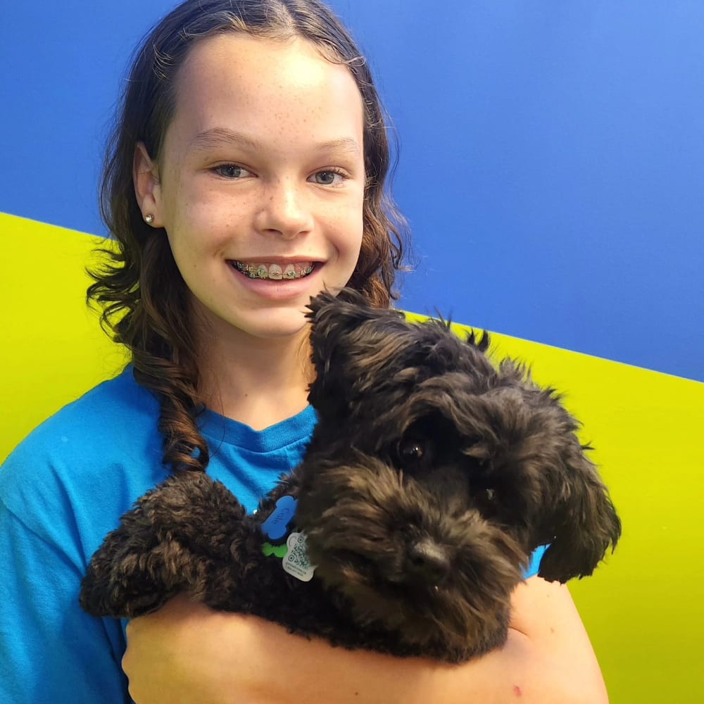 A patient at South Surrey Smiles shows off their braces while holding Cole the dog.