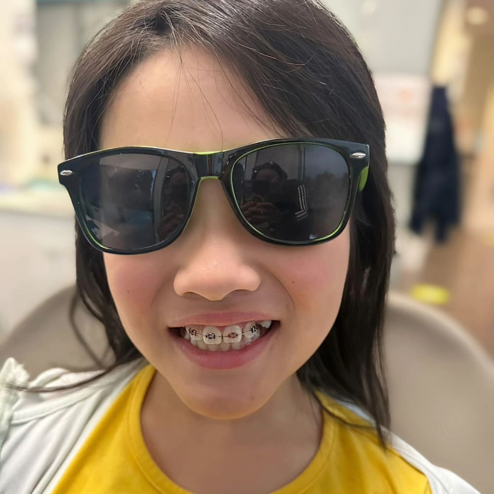 A young patient at Dr. Lesley Williams stands with a patient at South Surrey Smiles shows off their braces.