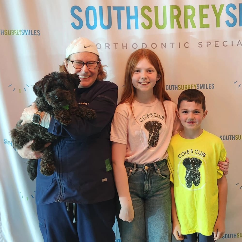 Dr. Lesley Williams is holding Cole the dog. Beside her, two kids are wearing shirts with Cole on them.