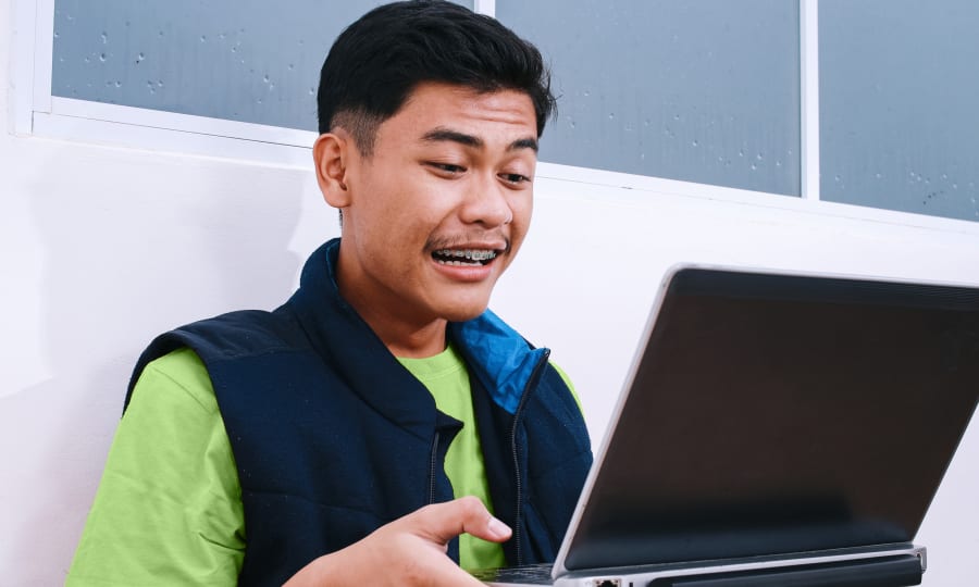 A patient with braces is looking into a laptop computer.