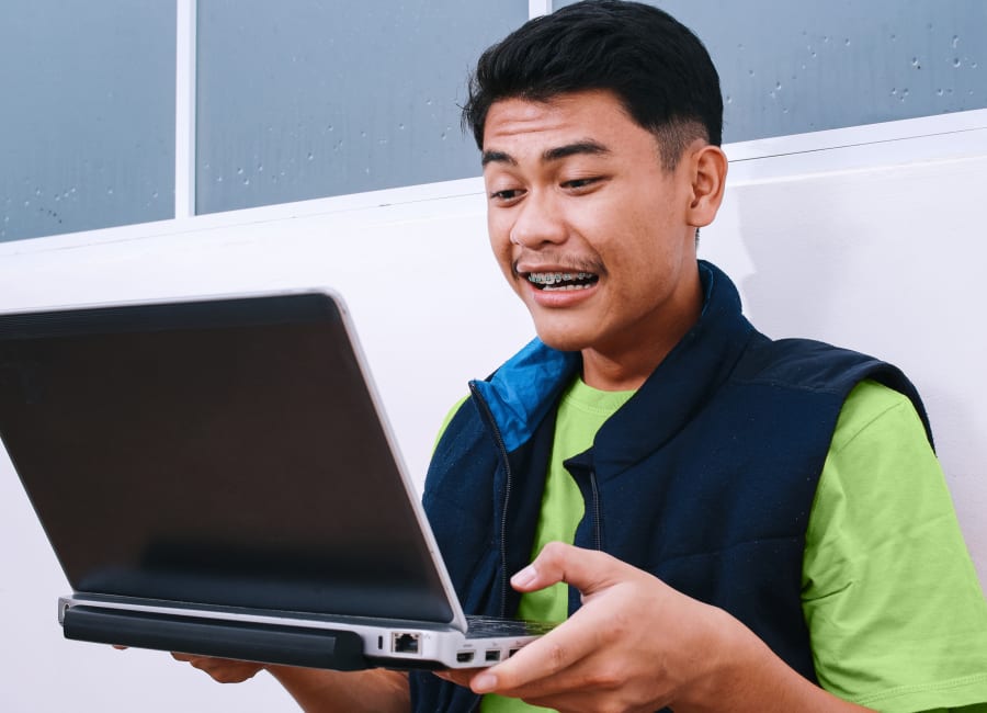 A patient with braces is looking into a laptop computer.