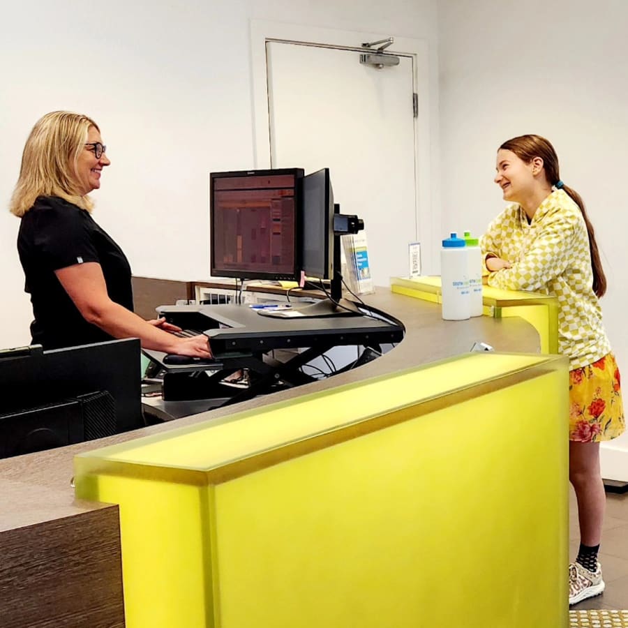 A patient stands at the Dr. Lesley Williams stands with a patient at South Surrey Smiles reception desk.