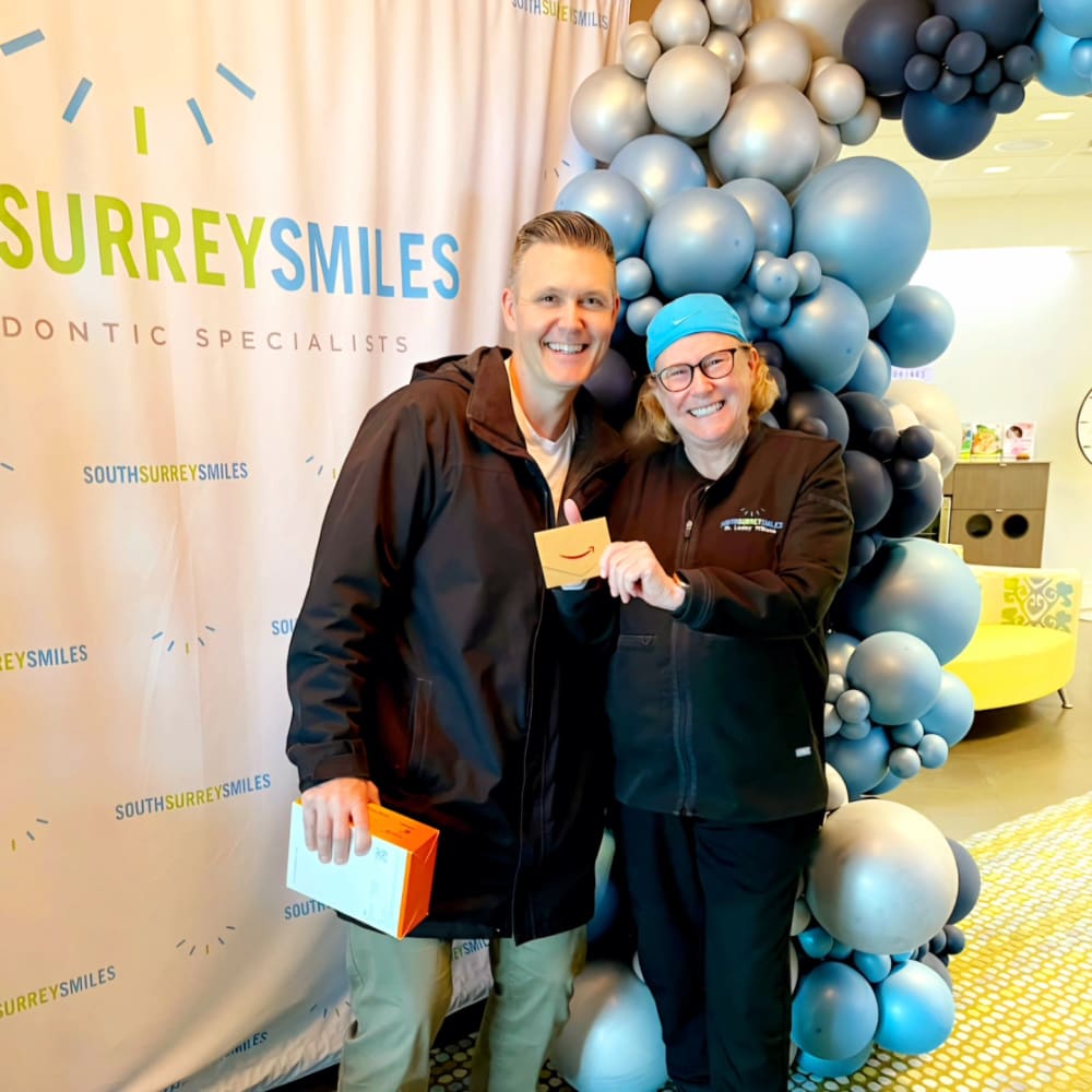 Dr. Lesley Williams standing next to an adult patient in front of blue balloons.