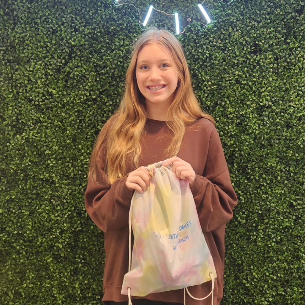 A teenage patient at Dr. Lesley Williams stands with a patient at South Surrey Smiles. smiles, showing off her braces.