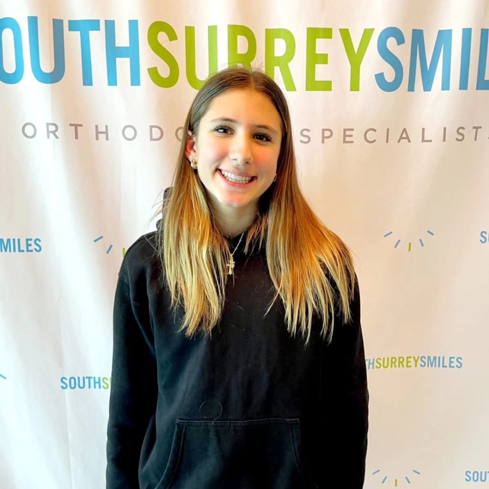 A teenage patient at Dr. Lesley Williams stands with a patient at South Surrey Smiles smiles, showing off straight teeth.